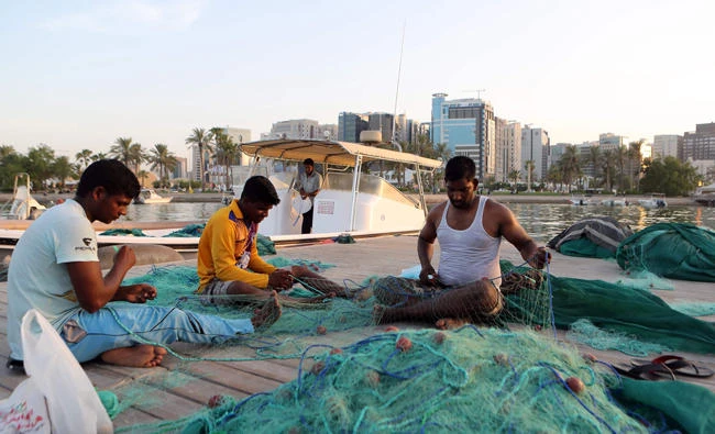 Fishermen fix a net on the corniche of the Qatari capital Doha on July 2, 2017. (AFP)