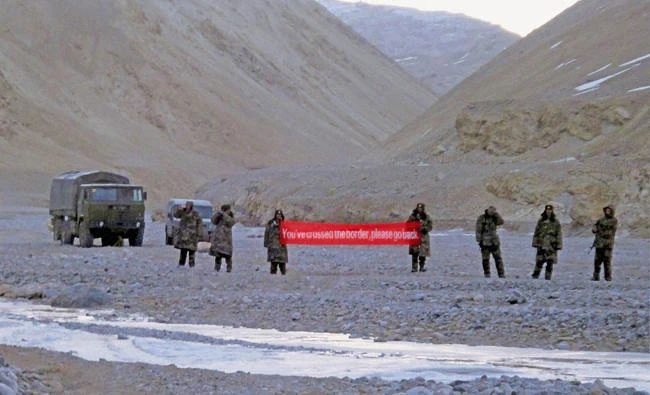 In this May 5, 2013, file photo, Chinese troops hold a banner which reads "You've crossed the border, please go back" in Ladakh, India. China is insisting that India withdraw its troops from a disputed Himalayan plateau before talks can take place to settle the most protracted standoff in recent years between the nuclear-armed neighbors. (AP Photo, File)