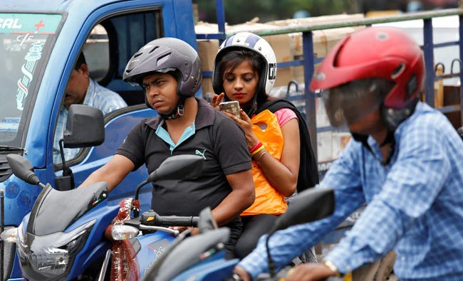 A woman checks her mobile phone at a traffic junction in Kolkata, India on July 5, 2017. India is examining the use of private vehicles as shared taxis in an effort to reduce car ownership and curb growing traffic congestion in major cities. (REUTERS)