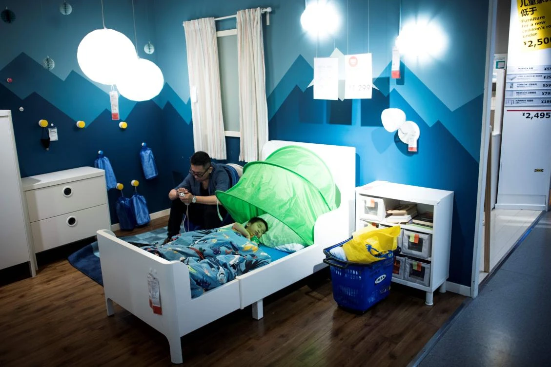 This picture taken on July 5, 2017 shows a father with his child escaping the summer heat by letting him sleepn in a bed in a Ikea store in downtown Shanghai. According to a local news paper Shanghai Meteorological Bureau recorded a temperature high of high of 36.2 degrees Celsius during that time. (AFP)