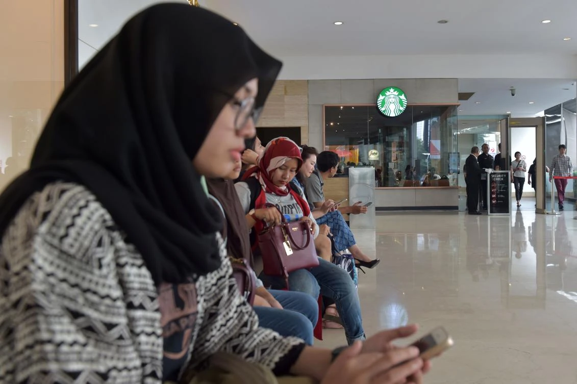 This photo taken on July 4, 2017 shows Indonesian Muslim women sitting outside a Starbucks cafe at a shopping mall in Jakarta. Muslims in Indonesia and Malaysia were urged to boycott Starbucks on July 4 by major Islamic groups accusing the coffee chain of being pro-gay rights, as concerns grow over rising religious conservatism in both nations. (AFP)
