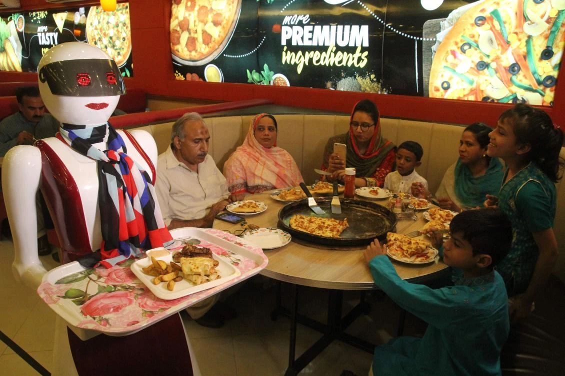In this photograph taken on July 4, 2017, a robot waitress delivers food at a pizza restaurant in Multan. Pakistan's first robot waitresses are serving up smiles for customers at an upscale pizza restaurant in the ancient city of Multan, better known for its centuries-old Sufi shrines, mango orchards and handicrafts. Rabia, Annie and Jennie greet customers and bring them their pies at Pizza.com, where owner Osama Jafari -- who built the prototypes himself -- says the response has been a surge of new business. (AFP)