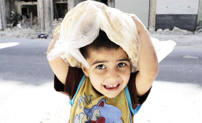 A Syrian girl holding a bread packet is on her way home in Al-Kalasseh district of the northern city of Aleppo. (AFP)