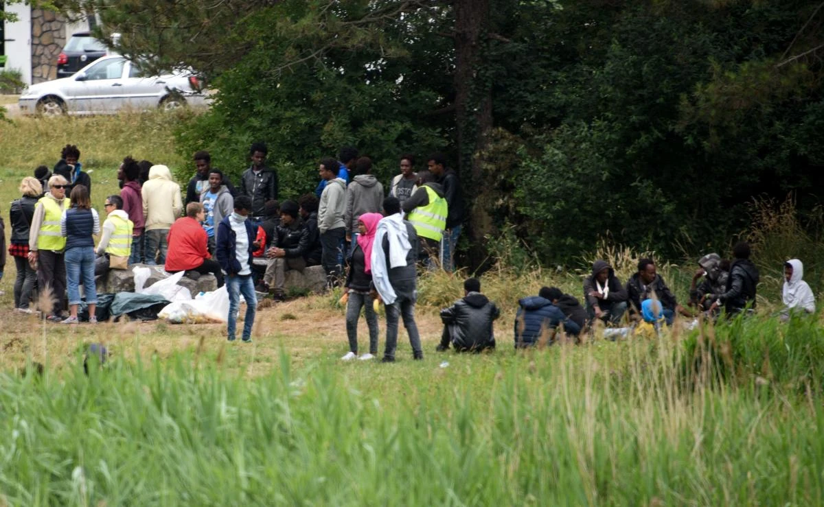 Migrants wait on a field near the ring road leading to the port of Calais, northern France. Calais has for years been a magnet for migrants and refugees hoping to cross the Channel to Britain. (AFP)