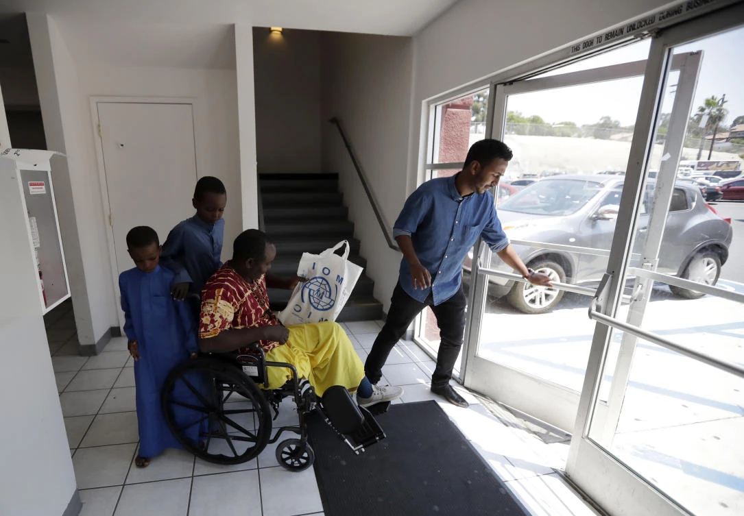 Ali Said, of Somalia, center, leaves a center for refugees with his two sons, as refugee caseworker Mohamed Yassin, right, holds open the door Thursday, July 6, 2017, in San Diego. (AP)