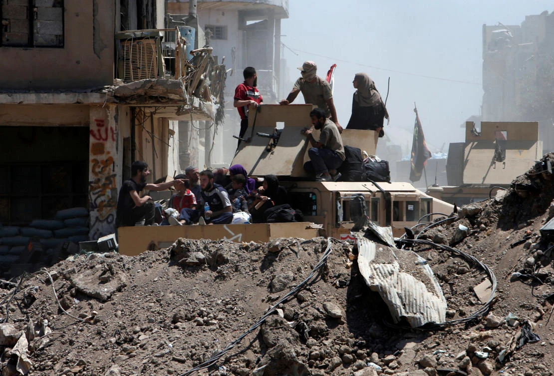 Displaced people who fled from clashes ride in a military vehicle of Iraqi security forces, in the Old City of Mosul, Iraq. (Reuters)
