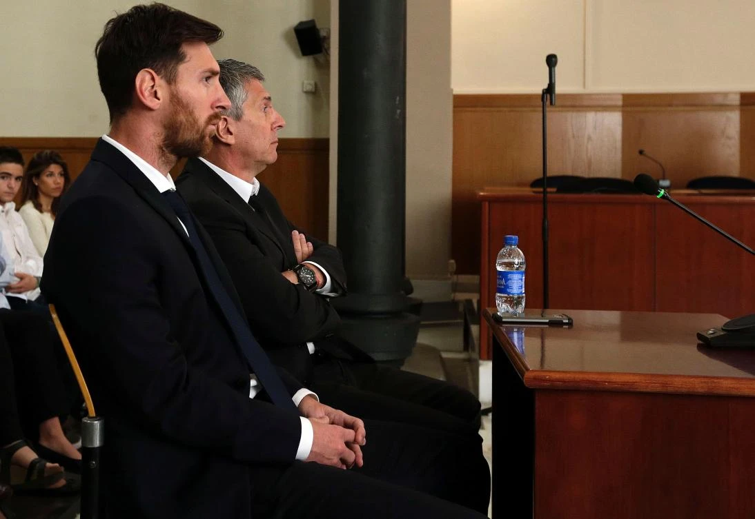 Barcelona's football star Lionel Messi (L) and his father Jorge Horacio Messi listening as they face judges in a tax fraud case at the courthouse in Barcelona. (AFP)