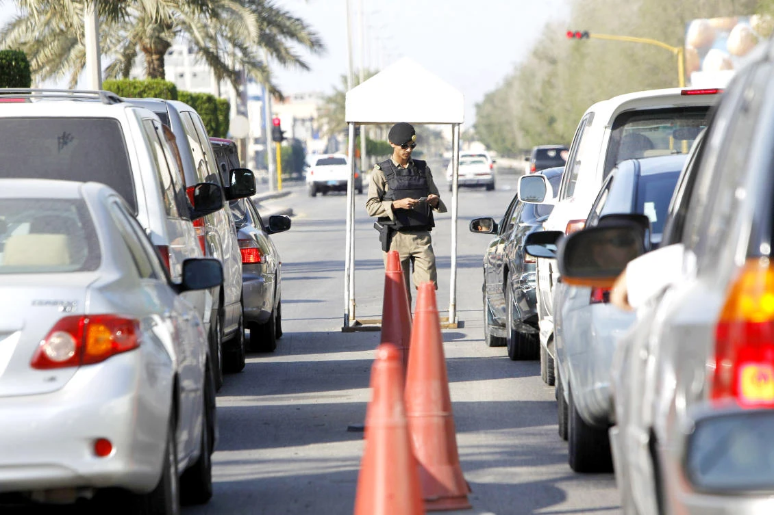 A security officer checks the documents of a motorist at a checkpoint in Qatif.