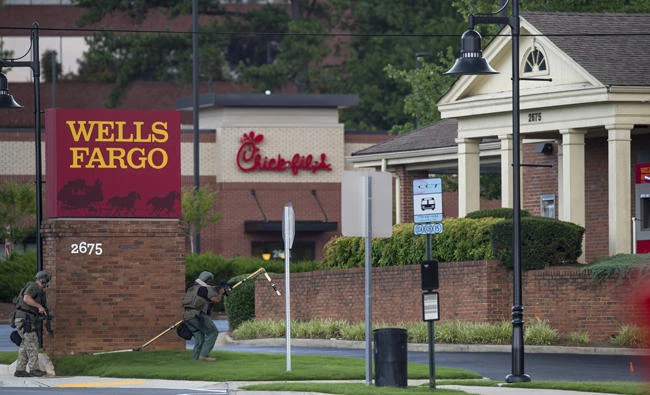 Police officers move toward a Wells Fargo Bank on July 7, 2017 in Marietta, Geogia, US. A man who claimed to have a bomb that could "take out the room" barricaded himself inside a suburban Atlanta bank Friday, sparking an hours-long standoff that forced police to bust through a brick wall of the building and later ended with the suspect's death.(AP Photo/Mike Stewart)