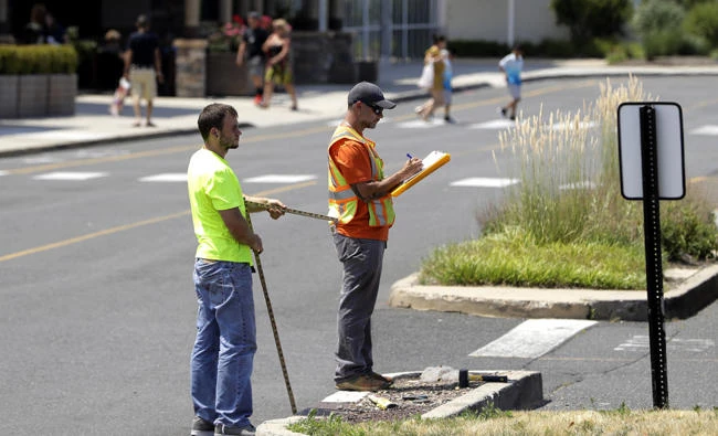 In this July 5, 2017, photo, two men survey an area in the parking lot of Monmouth Mall in Eatontown, New Jersey. Four local women are the plaintiffs in a court case against the town, which they claim gave Kushner Cos. special treatment and sped through approvals for its proposal to build an apartment complex on the mall parking lot. (AP Photo/Julio Cortez)