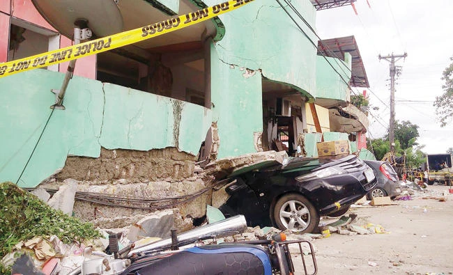 Vehicles are buried under the rubble of a destroyed building a day after a 6.5 magnitude earthquake hit the town of Kananga, Leyte province, central Philippines on Friday. (AFP)