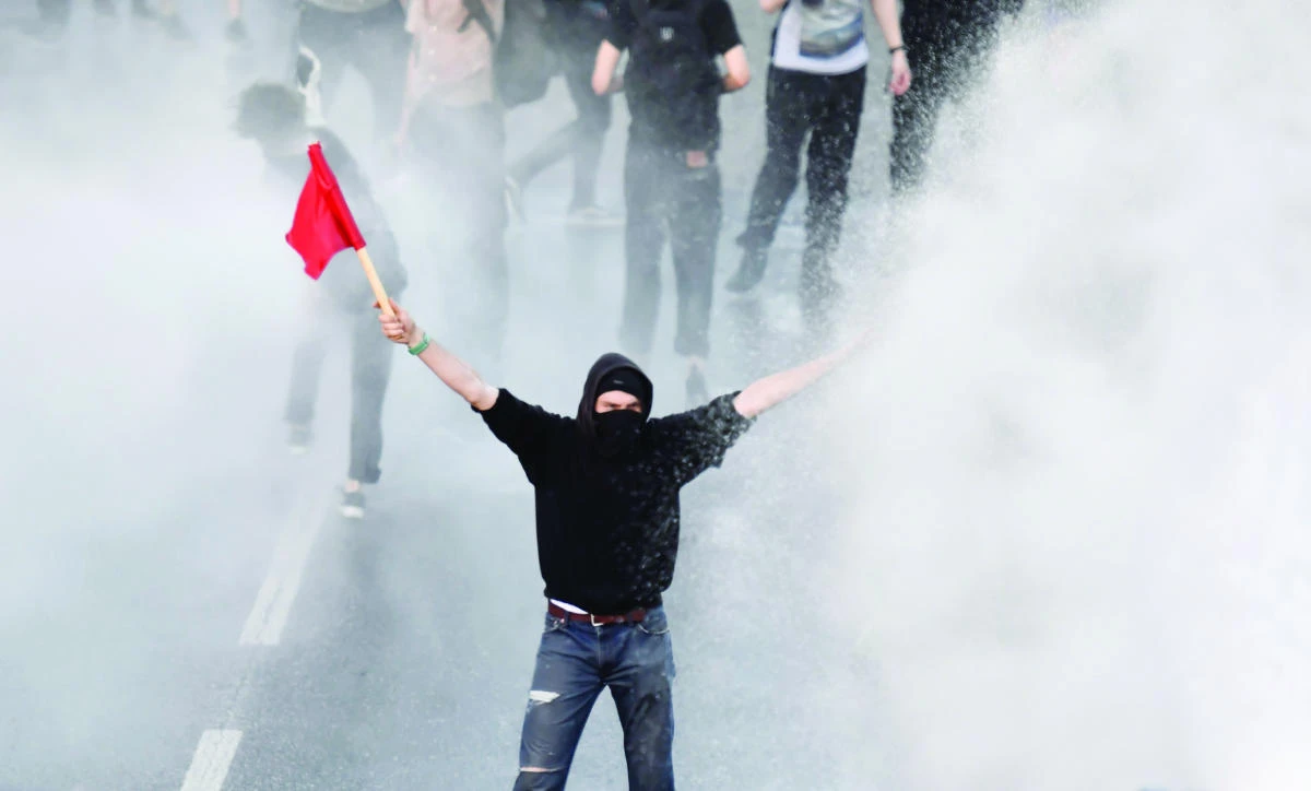 Police use water cannon toward a protester with a red flag during the "Welcome to Hell" rally against the G-20 Summit in Hamburg, northern Germany on Thursday. (AFP)