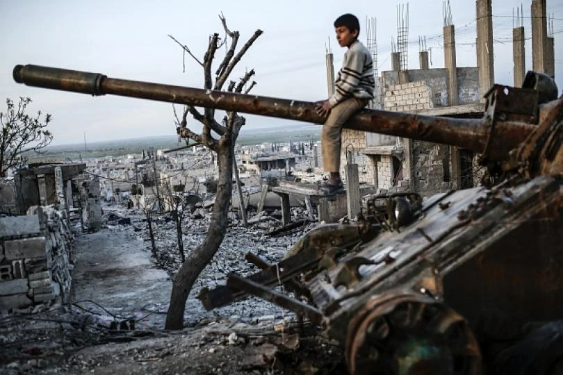 A Syrian Kurdish boy sits on a destroyed tank in the Syrian town of Kobane, also known as Ain al-Arab, on March 27, 2015. (AFP)