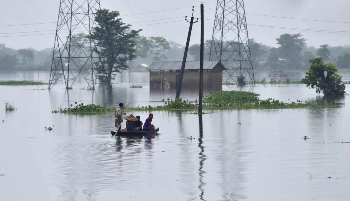 Indian villagers travel on a boat through a flooded village near Kaziranga National Park, about 250 kilometres east of Guwahati, on July 10, 2017. / AFP / Biju BORO