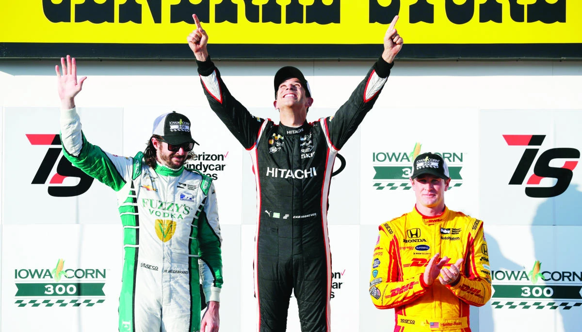 Helio Castroneves, center, of Brazil, celebrates in Victory Lane with second-place finisher JR Hildebrand, left, and third-place finisher Ryan Hunter-Reay, right, after winning a IndyCar Series auto race Sunday at Iowa Speedway in Newton, Iowa. (AP)