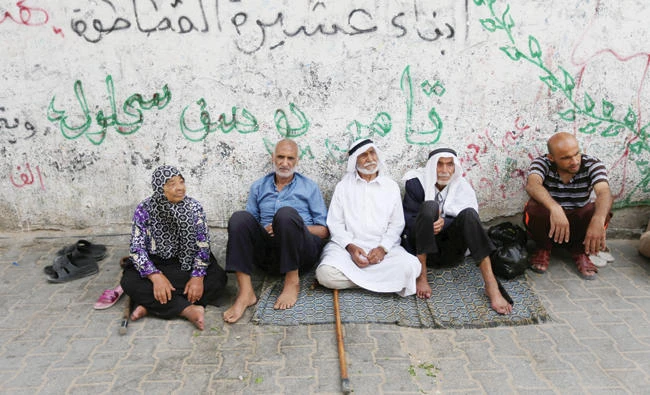 Palestinians sit outside their houses in Khan Younis refugee camp in the southern Gaza Strip on Tuesday. (Reuters)