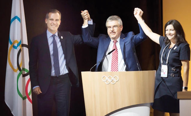 Eric Garcetti, mayor of Los Angeles, left, International Olympic Committee (IOC) President Thomas Bach, center, and Anne Hidalgo, mayor of Paris, pose together during the IOC Extraordinary Session at the Swiss Tech Convention Centre in Lausanne Tuesday. (AP)