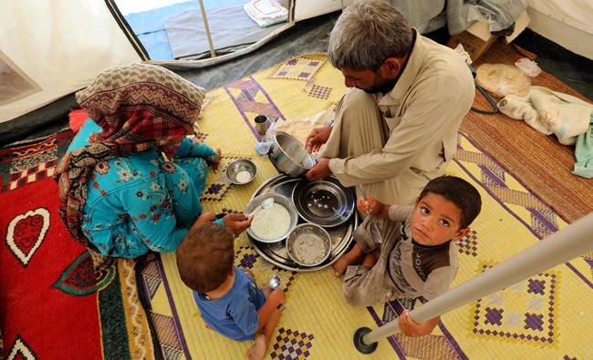 A displaced Syrian family, who fled the countryside surrounding Daesh’s stronghold of Raqqa, share a meal at a camp in Ain Issa on Tuesday. (AFP)