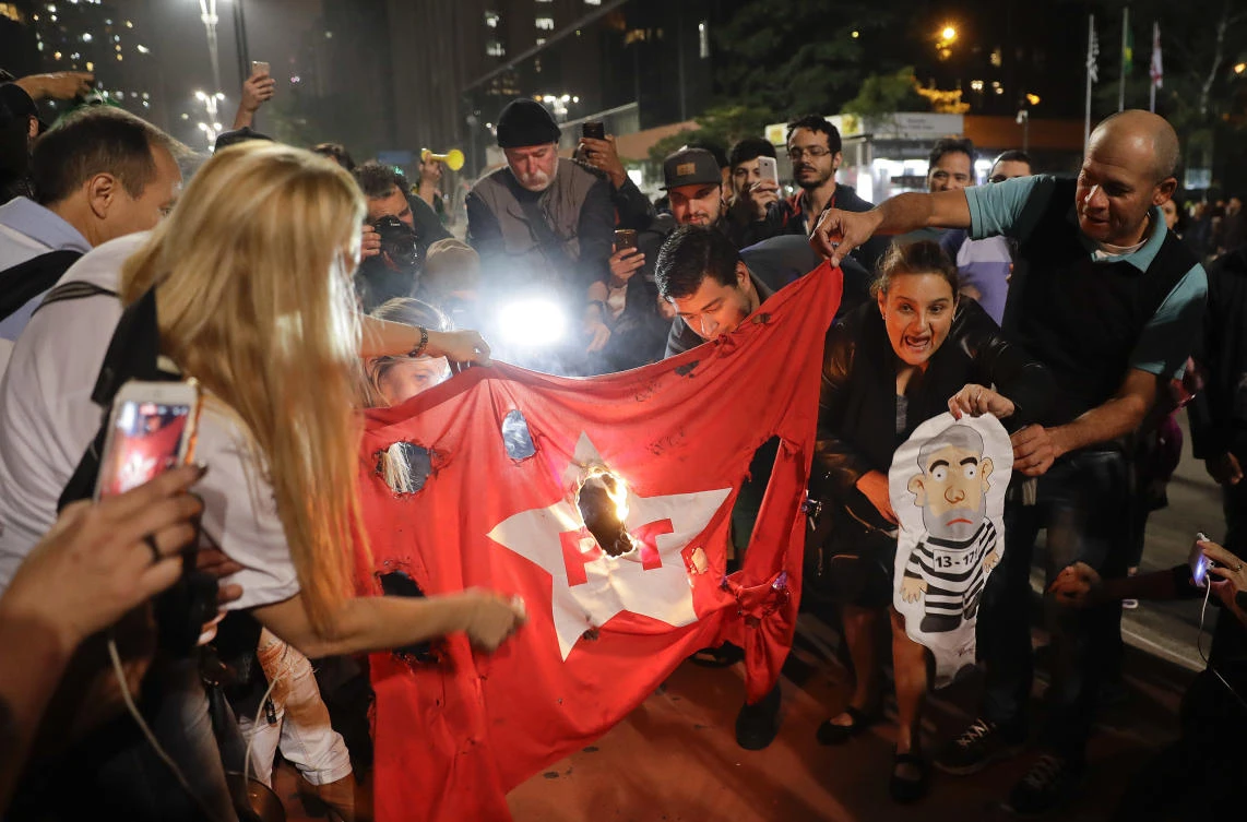 Demonstrators set fire to a Workers Party flag and hold a doll of former President Luiz Inacio Lula da Silva in prison garb, as they celebrate the decision by Judge Sergio Moro to convict Lula da Silva, in Sao Paulo, Brazil, Wednesday, July 12, 2017. Lula da Silva was found guilty of corruption and money laundering Wednesday and sentenced to almost 10 years in prison. (AP)