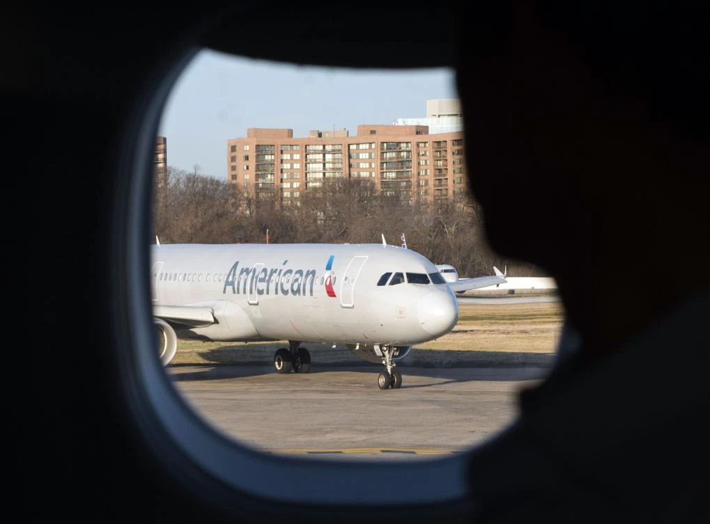 (FILES) This file photo taken on February 24, 2017 shows a passenger looking out his window at an American Airlines plane at Reagan National Airport in Arlington, Virginia. American Airlines said on July 12, 2017, it is ending its codeshare relationships with Qatar Airways and Etihad Airways as part of its push against government subsidies of Middle Eastern carriers. American notified Doha-based Qatar Airways and Abu Dhabi-based Etihad of its decision on June 29 to end the "codeshare" partnership -- the sharing of a flight by two carriers. (AFP)
