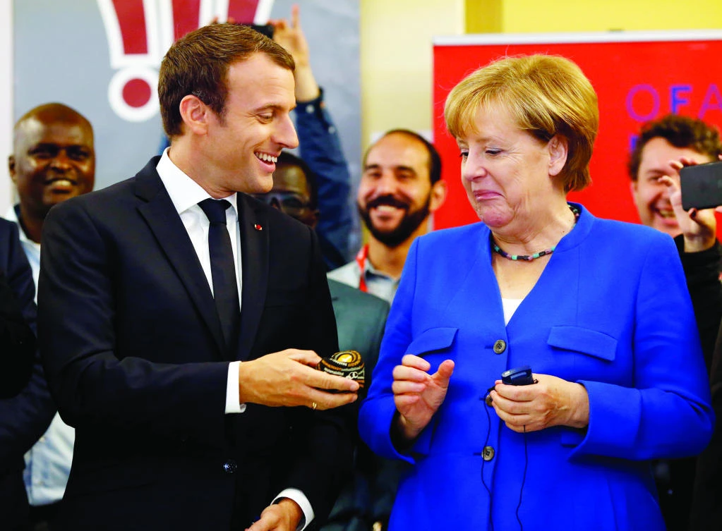 French President Emmanuel Macron offers a soft ball to German Chancellor Angela Merkel, as they visit the Franco-German Youth Office in Paris, on Thursday. (Reuters)