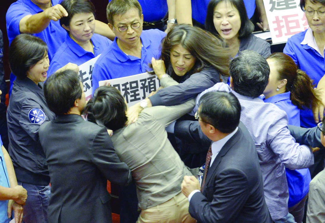 Two Taiwanese lawmakers try to choke each other during a brawl in the island’s Parliament, in Taipei on Thursday. (AFP)