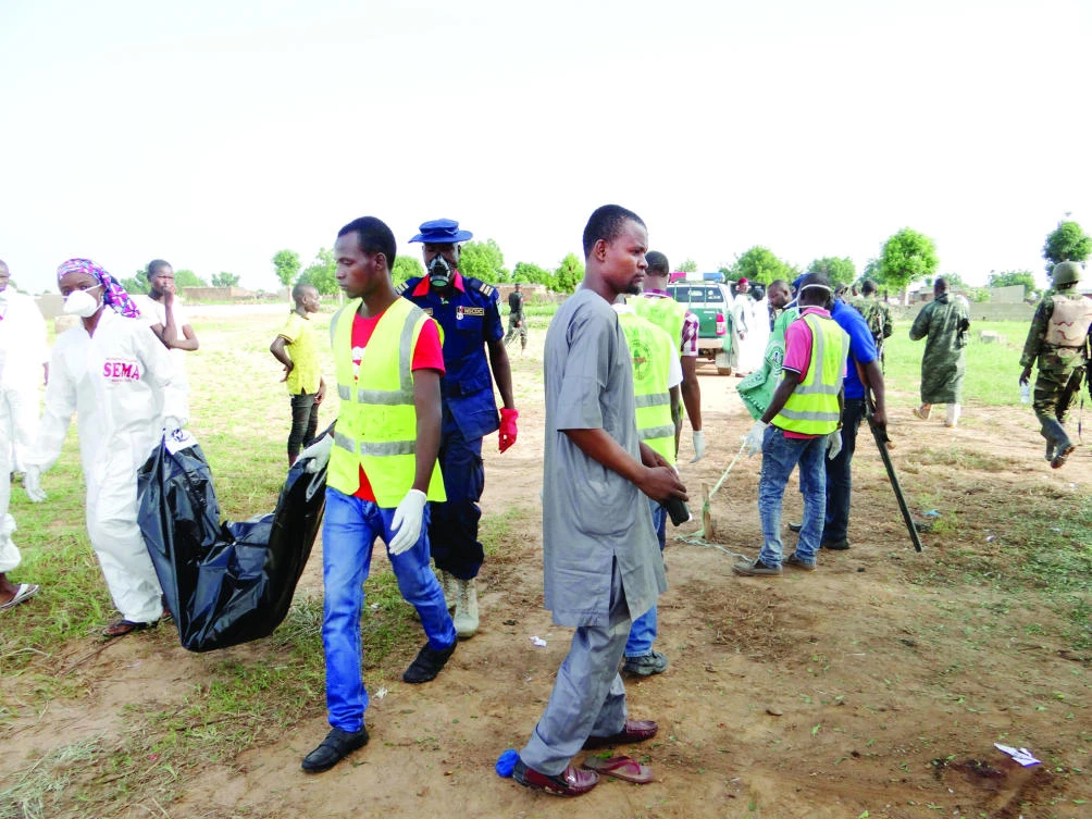 Rescue workers carry the body of a suicide bomb attack victim in a village near Maiduguri, Nigeria, on Wednesday. (AP)