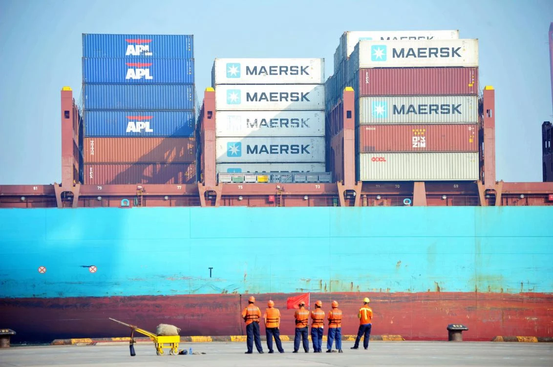 Chinese workers look as a cargo ship is loaded at a port in Qingdao, eastern China's Shandong province. (AFP)