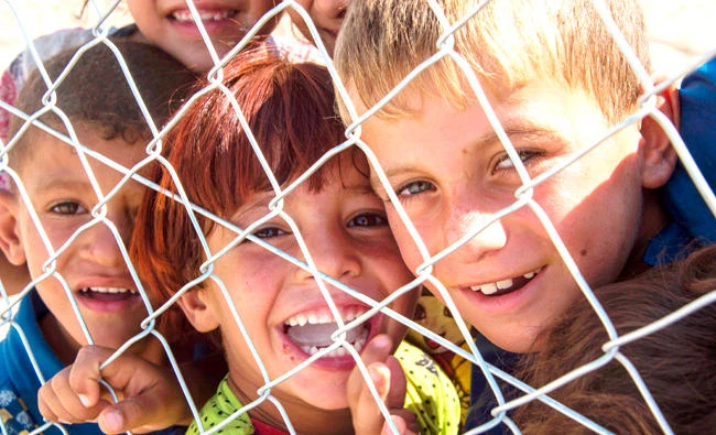 Children look through a fence at a refugee camp run by the UN High Commissioner for Refugees (UNHCR) in Hammam Al-Alil, on the outskirts of Mosul. (AFP)
