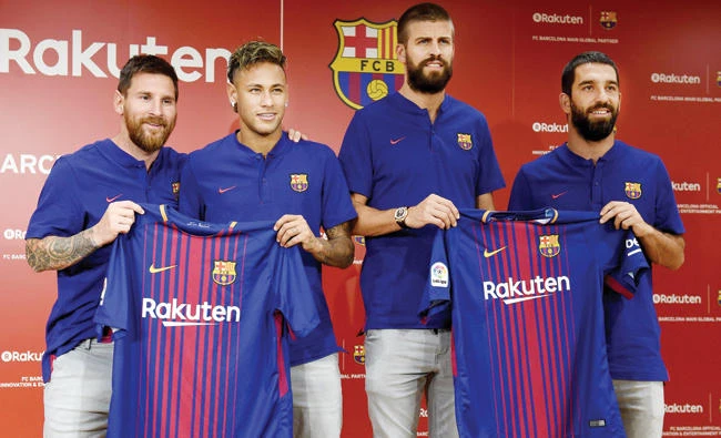 FC Barcelona players Lionel Messi, left, Neymar, second left, Gerard Pique, second right, and Arda Turan show off their new jersey with the Rakuten sponsorship logo for the first time during a press conference in Tokyo on Thursday. (AFP)