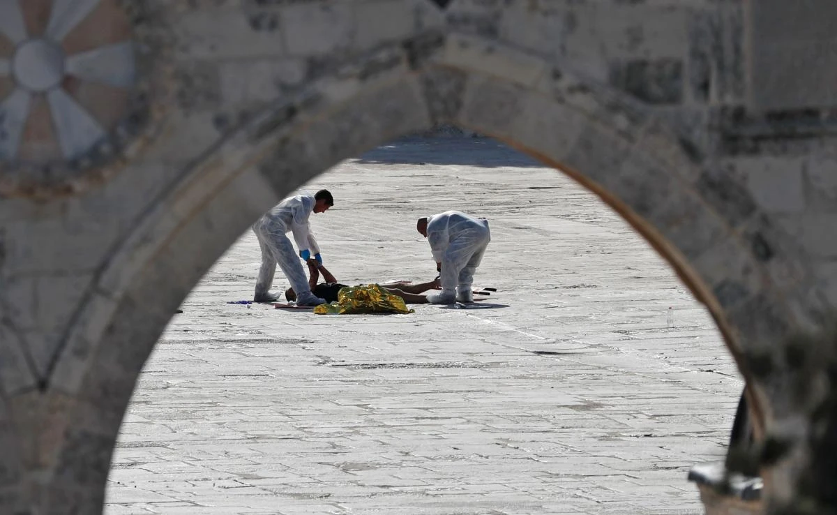 Israeli police check the scene and surround a dead body (in foreground) where assailants allegedly fired shots toward Israeli forces on the Al Aqsa mosque compound in the Jerusalem’s Old City on July 14, 2017. (AFP)