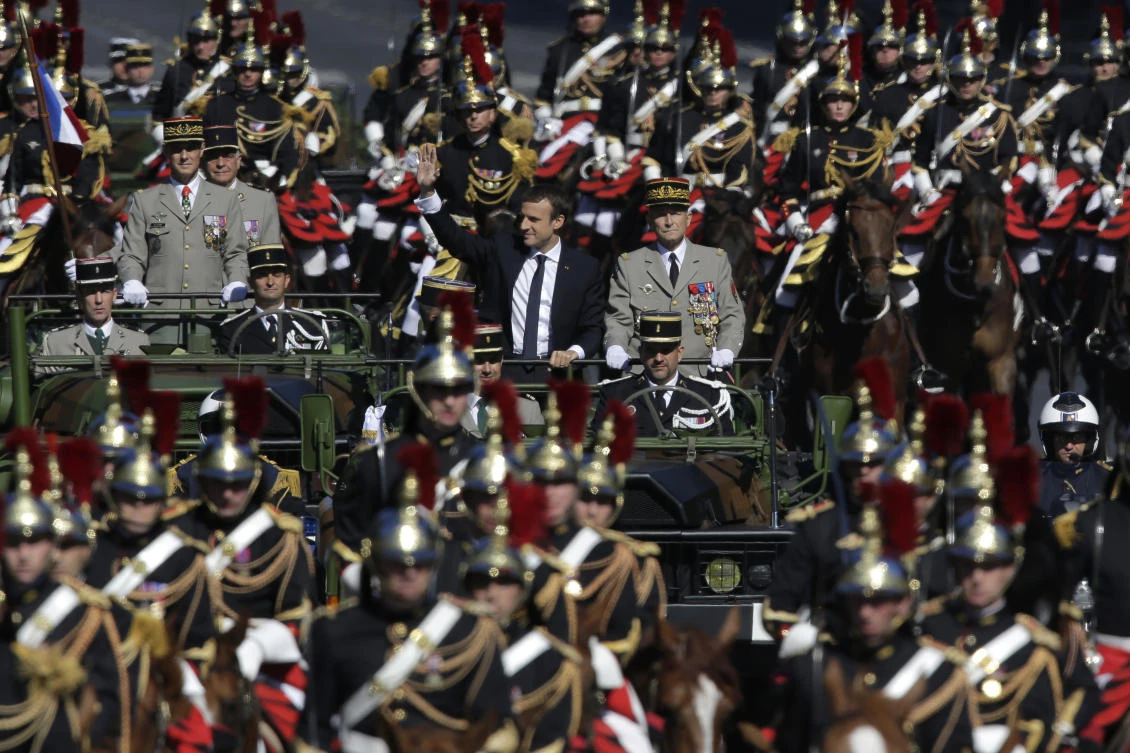 French President Emmanuel Macron, left, and Chief of the Defense Staff Gen. Pierre de Villiers, right, drive down the Champs Elysees avenue during Bastille Day parade in Paris. (AP)
