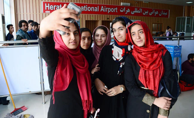 Afghan teenagers from the Afghanistan Robotic House taking pictures with a mobile phones at Herat International Airport, before embarking for the United States. A team of Afghan girls who were earlier denied visas to attend a Washington robotics competition landed in the United States early Saturday following an intervention by US President Donald Trump on Saturday. (AFP)
