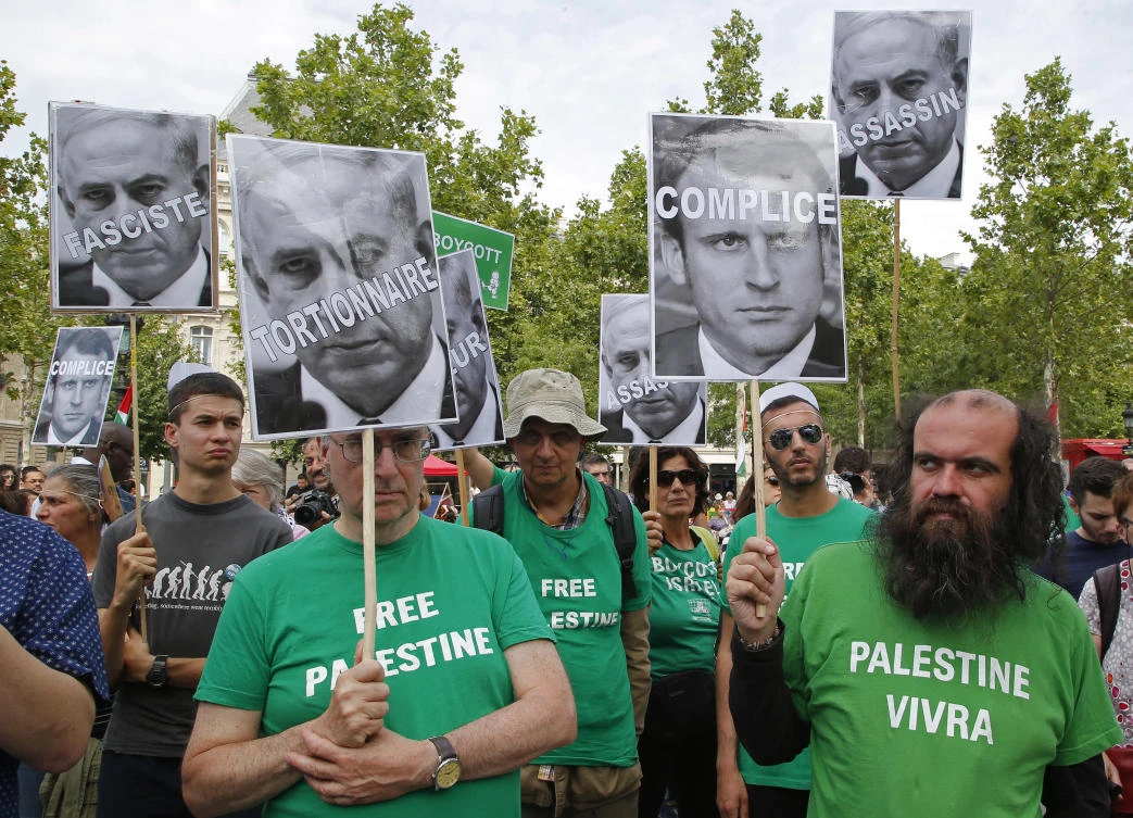 Pro-Palestinian activists hold pictures of Israeli Prime Minister Benjamin Netanyahu and French President Emmanuel Macron as they gather to protest Israeli Prime Minister's visit to France in Paris, Saturday, July 15, 2017.(AP)