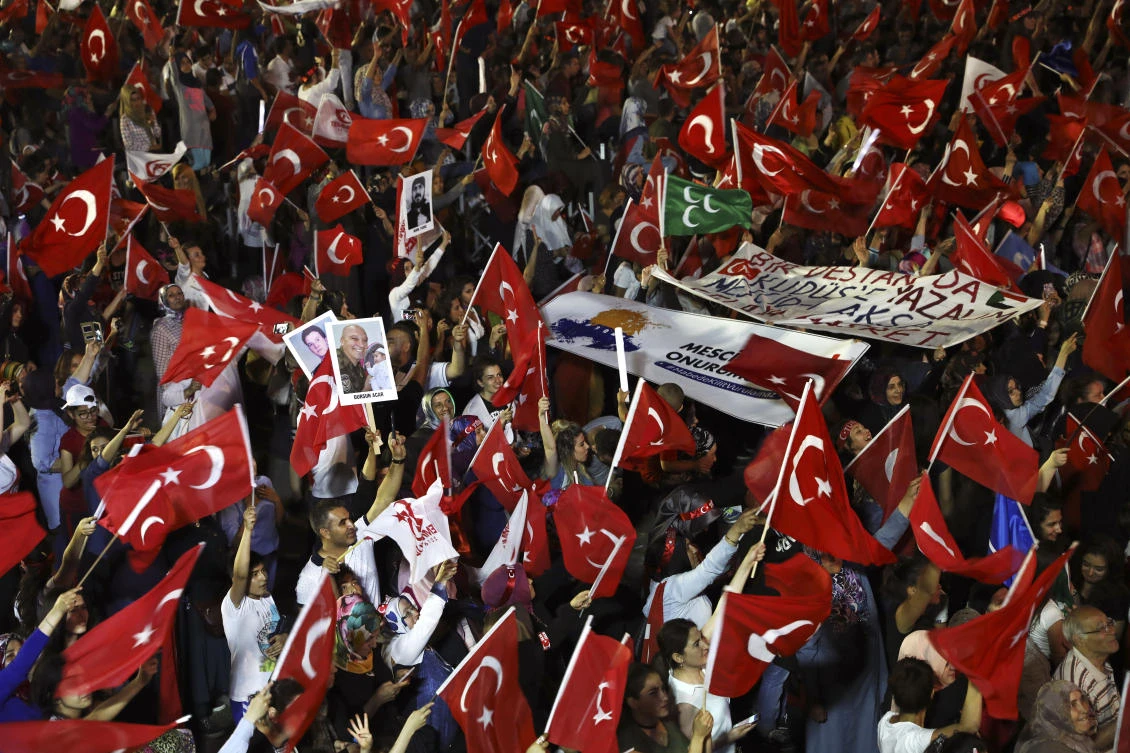 People wave the flags during a ceremony to commemorate the one year anniversary of the July 15, 2016 failed coup attempt, at Turkey's Parliament in Ankara, Turkey, early Sunday, July 16, 2017. (AP Photos/Ali Unal)
