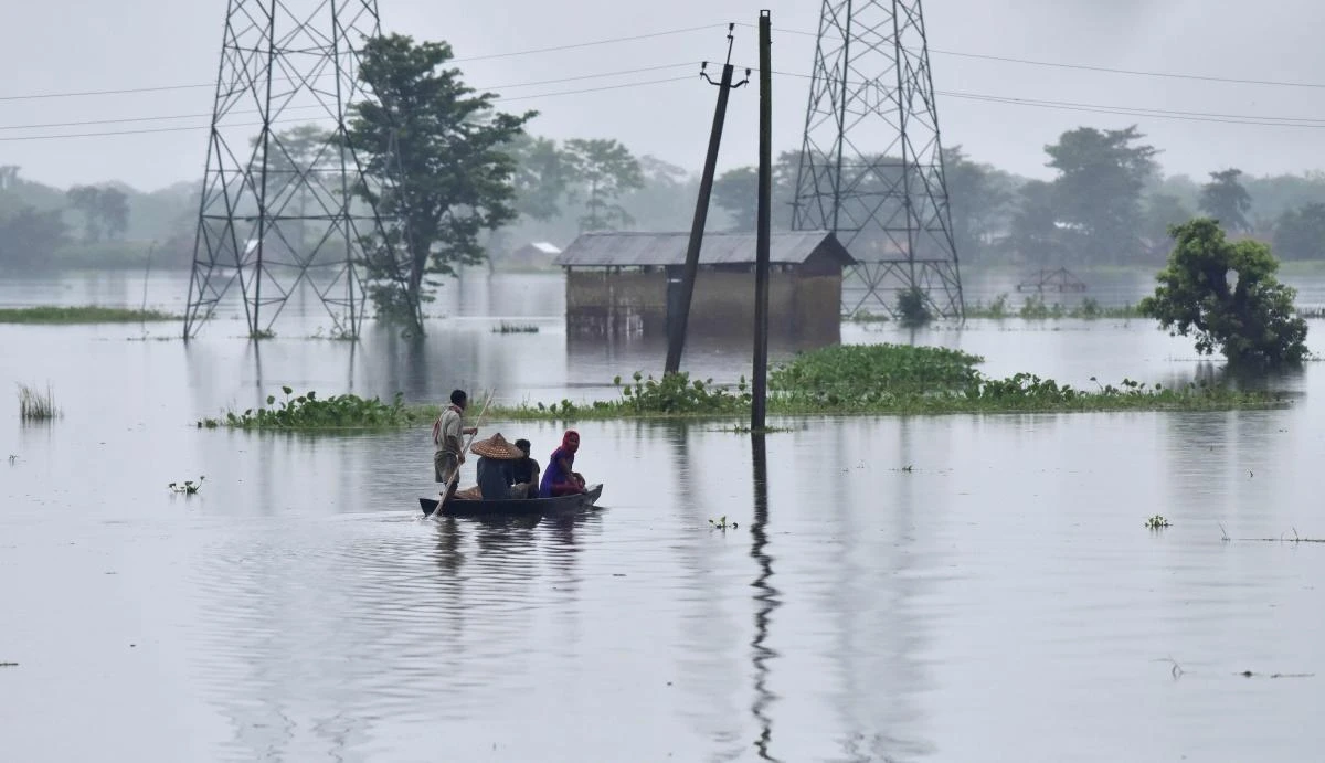(FILES) In this photograph taken on July 10, 2017, Indian villagers travel on a boat through a flooded village near Kaziranga National Park, about 250 kilometres east of Guwahati in the northeastern state of Assam. At least five people were killed and 10 missing July 11 after a massive landslide buried homes in a remote village in northeast India, a disaster management official said. An avalanche of mud and rock struck the village after weeks of heavy rain in Papum Pare district in the Himalayan state of Arunachal Pradesh along the border with China. (AFP)