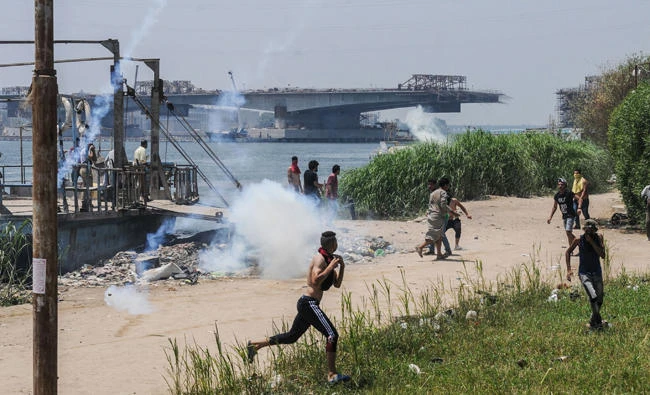 Egyptians run for cover from tear gas during clashes with security forces in the Nile island of Warraq in Giza province, north of the capital Cairo, on July 16, 2017. (AFP)
