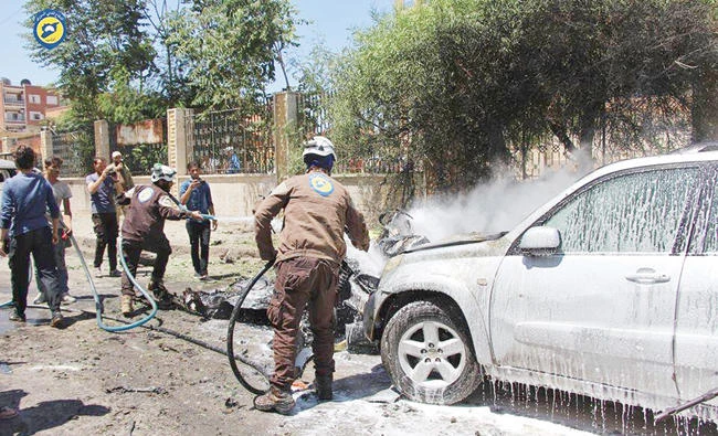 Rescue workers extinguish a burning car after an explosion in Idlib, Syria, on Sunday. (AP)