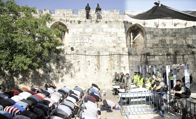 Palestinian worshippers, who refuse to enter Al-Aqsa Mosque compound due to Israel’s new security measures, pray near a main entrance to the religious site in Jerusalem’s Old City, on Sunday. (AP)