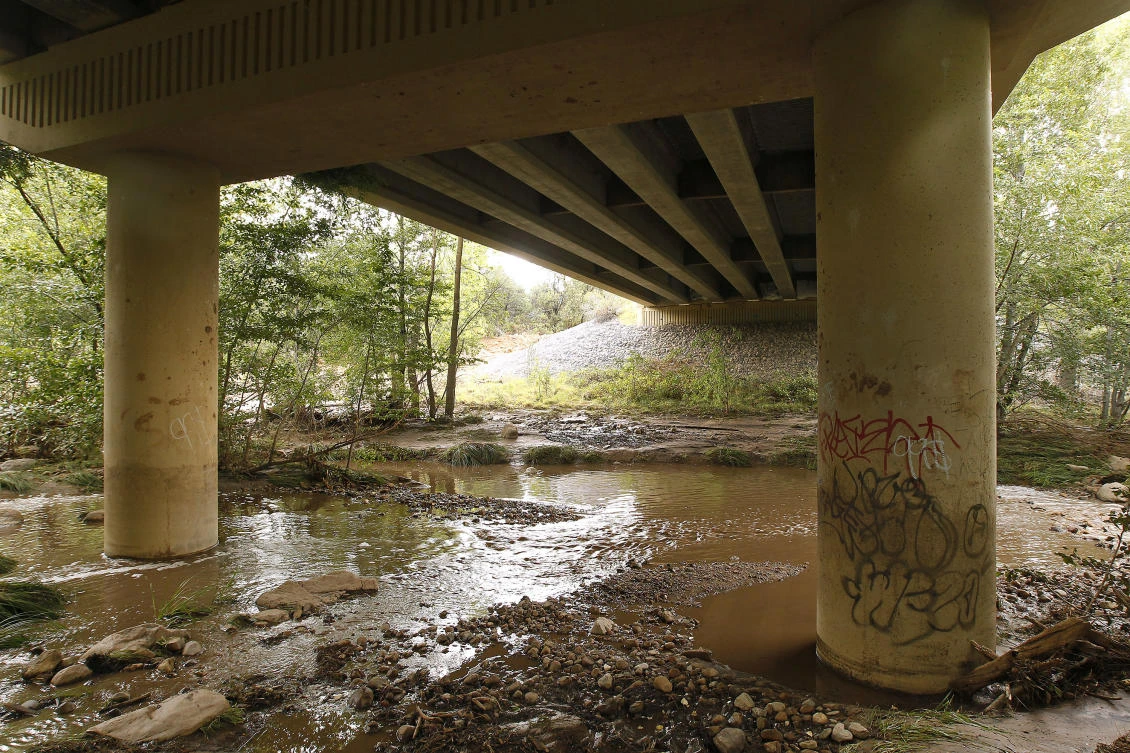 Muddy floodwaters of the East Verde River flow under a bridge were at least one victim of a flash flood was found during a search and rescue operation by the Gila County Sheriff's Office on Sunday, July 16, 2017, in Payson, Arizona. (AP Photo/Ralph Freso)