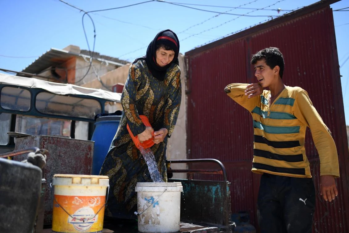 50-Year-Old Syrian Warda al-Jasim (L) fills a plastic bucket with water for her grape vine, upon returning to her home five weeks after leaving, in western of Raqa on July 15, 2017, during an offensive by the Syrian Democratic Forces (SDF), an alliance of Kurdish and Arab fighters, to retake the city from Islamic State (IS) group fighters. The US-backed coalition has captured around 30 percent of Raqa city since it entered the IS bastion in June after a months-long operation to capture territory in the surrounding province. (AFP)