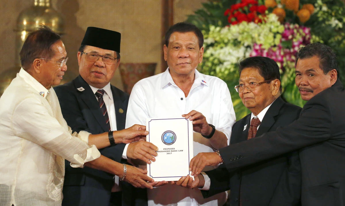 Philippine President Rodrigo Duterte, center, holds the draft of the Bangsamoro Basic Law (BBL) together with MILF and other leaders Monday in Manila. (AP)