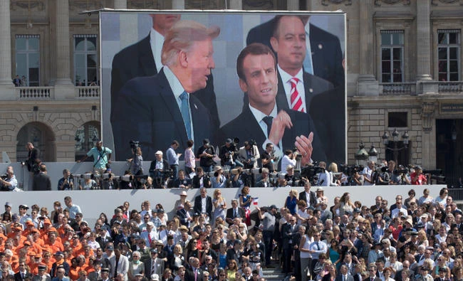 President Donald Trump, French President Emmanuel Macron and White House Chief of Staff Reince Priebus are seen on a large video screen during Bastille Day parade on the Champs Elysees avenue in Paris on July 14, 2017. (AP)