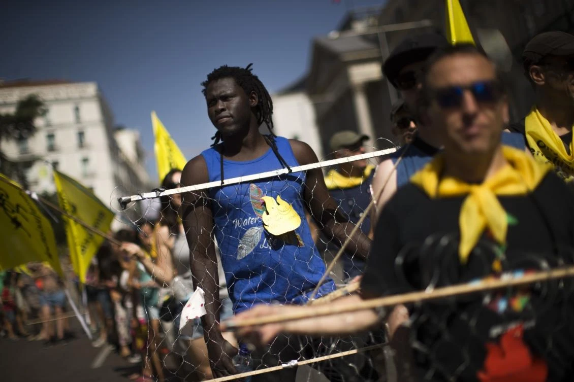 A demonstrator carries wire representing border razor wire fences, as he marches with others during a protest in support of migrant people seeking to enter Europe, in Madrid, Saturday, July 15, 2017. (AP)