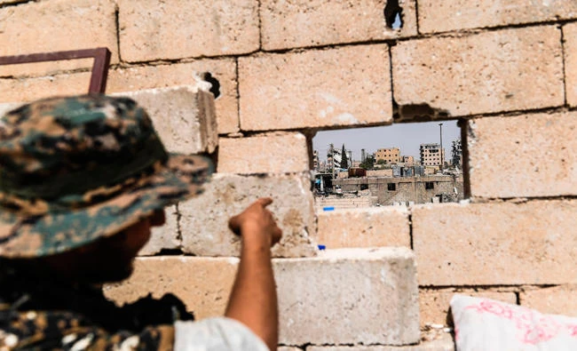 A member of the Syrian Democratic Forces, an alliance of Kurdish and Arab fighters, points at sniper positions of Daesh fighters in western Raqa on July 17, 2017. (AFP)