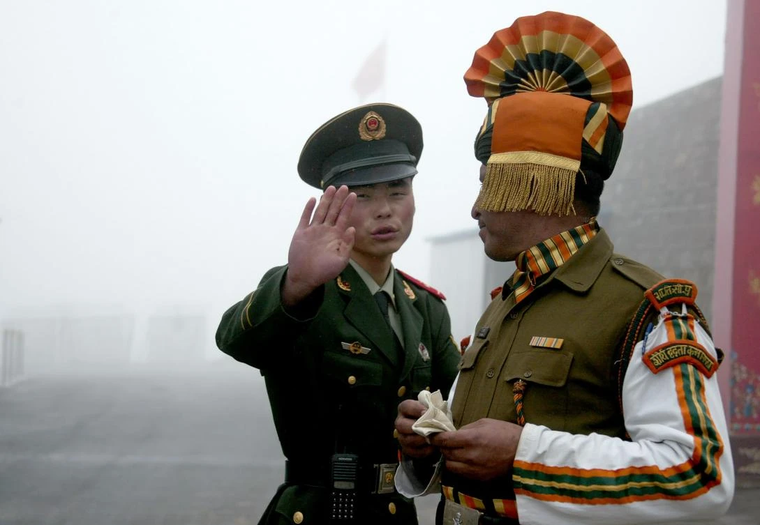 (FILES) This file photo taken on July 10, 2008 shows a Chinese soldier (L) next to an Indian soldier at the Nathu La border crossing between India and China in India's northeastern Sikkim state. China's ambassador said July 4, 2017 that the withdrawal of Indian troops from a disputed territory is a "precondition" for peace, in an apparent escalation of a border row between the two Asian powers that has drawn in tiny Bhutan. Indian and Chinese troops are reportedly facing off on a section of land high in the Himalayas near what is known as the trijunction, where Tibet, India and Bhutan meet. (AFP)