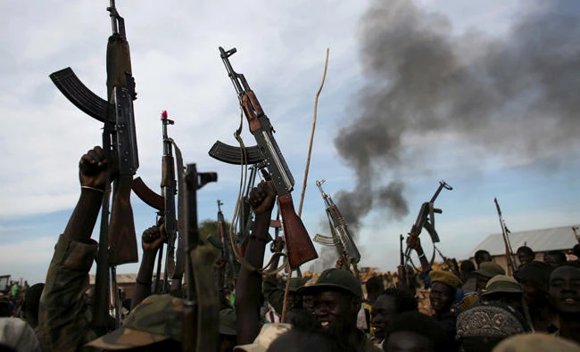 Rebel fighters hold up their rifles as they walk in front of a bushfire in a rebel-controlled territory in Upper Nile State, South Sudan in this file photo. (Reuters)