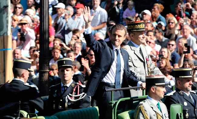 French President Emmanuel Macron, left, and Army Gen. Pierre de Villiers riding aboard a command car during the annual Bastille Day military parade on the Champs-Elysees avenue in Paris in this July 14 photo. (AFP)