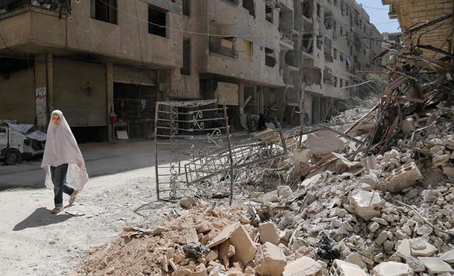 A girl walks past the rubble of a destroyed building down a street in the rebel-held Syrian town of Ayn Tarma, in the Ghouta area east of the capital Damascus on Wednesday. (AFP)