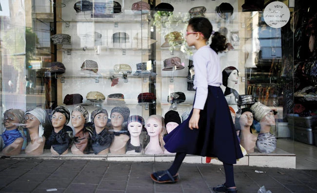 An ultra-Orthodox Jewish girl walks past a shop in Bnei Brak, Israel, on Tuesday. (Reuters)